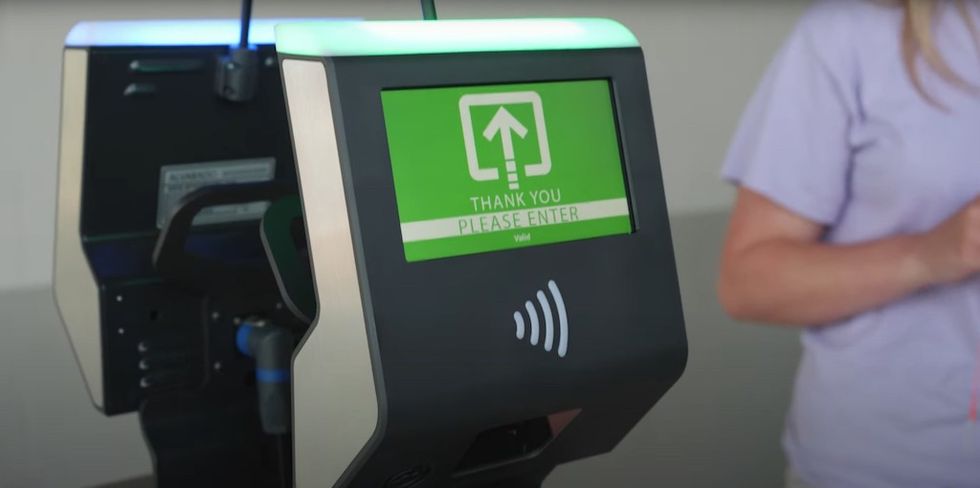 Electronic kiosk with "Thank You, Please Enter" message and a person nearby.