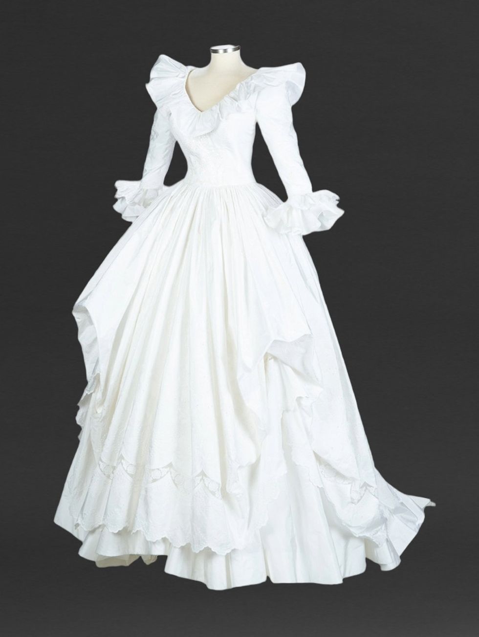 Elegant white wedding dress with ruffled neckline and sleeves, displayed on mannequin.