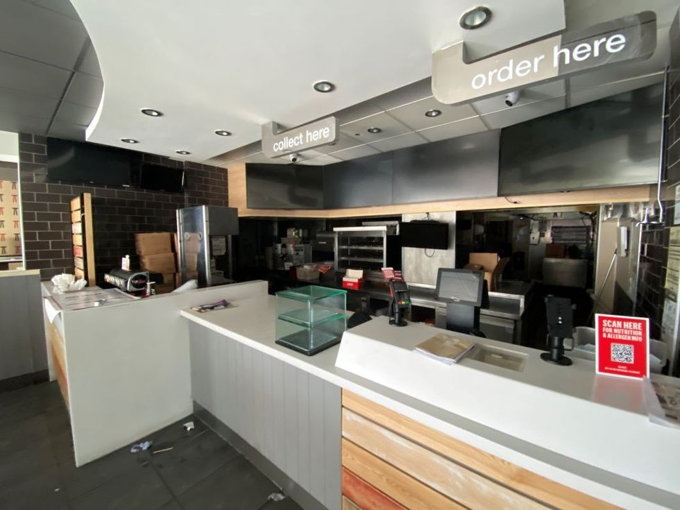 Empty fast-food restaurant counter with order and collect signs.