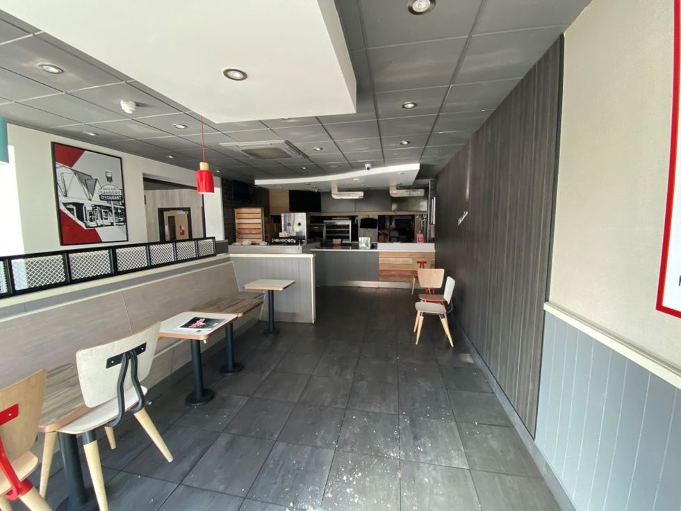 Empty fast food restaurant interior with tables, chairs, and a front counter.