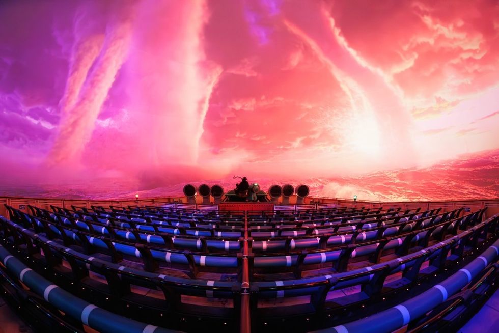 Empty theater with vibrant pink sky and tornadoes on the screen.