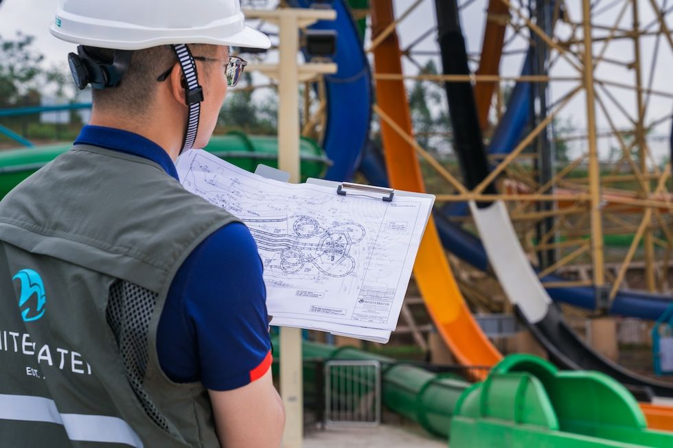 Engineer in hard hat reviewing plans at a construction site with colorful structures.