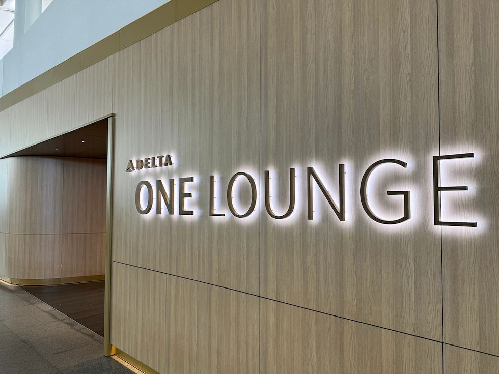 Entrance to Delta One Lounge with illuminated sign on wooden wall.