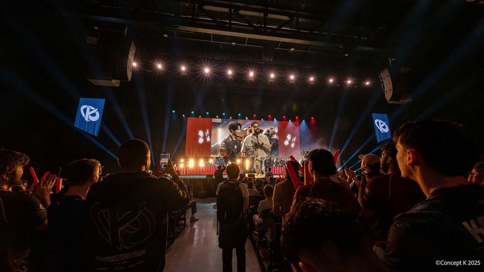 Esports event with players on stage and cheering audience.