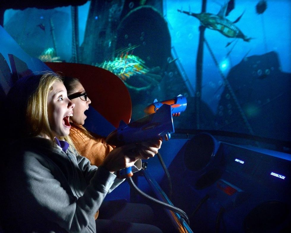 Excited people playing an underwater-themed interactive shooting game.