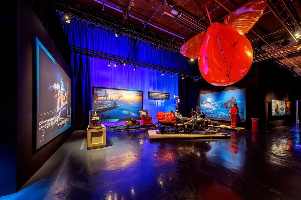 Exhibit in \u200bPolar Experience with polar exploration theme, featuring large images, artifacts, and red balloon object.