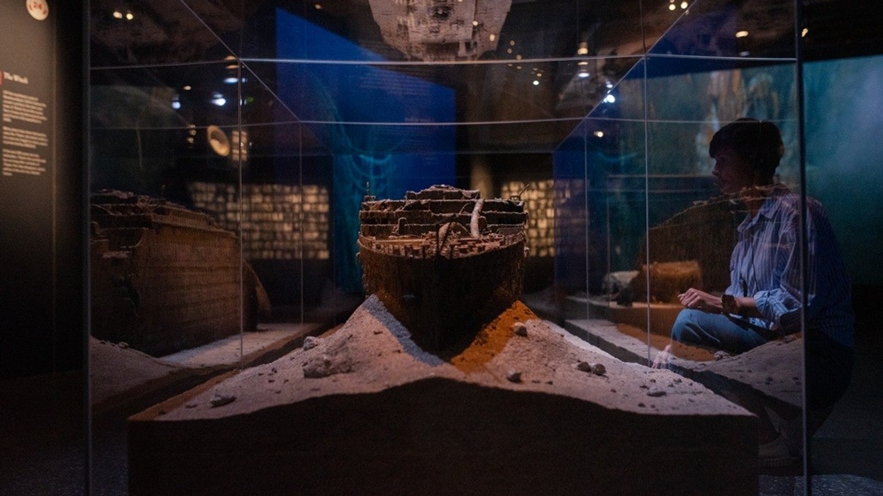 Exhibit of a shipwreck model in a dimly lit museum display case.