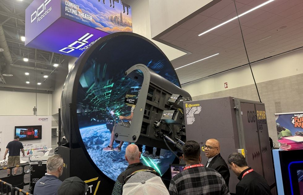 Exhibit of DOF Robotics' Compact Flying Theater with attendees watching a demonstration.