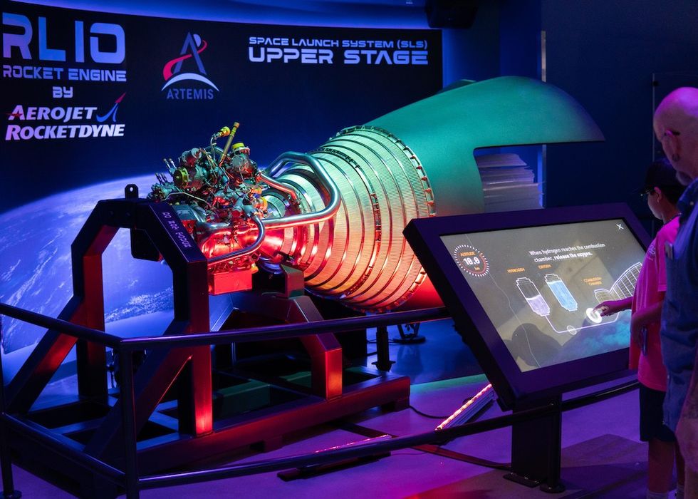 Exhibit of the RL10 rocket engine with interactive display at a space center.