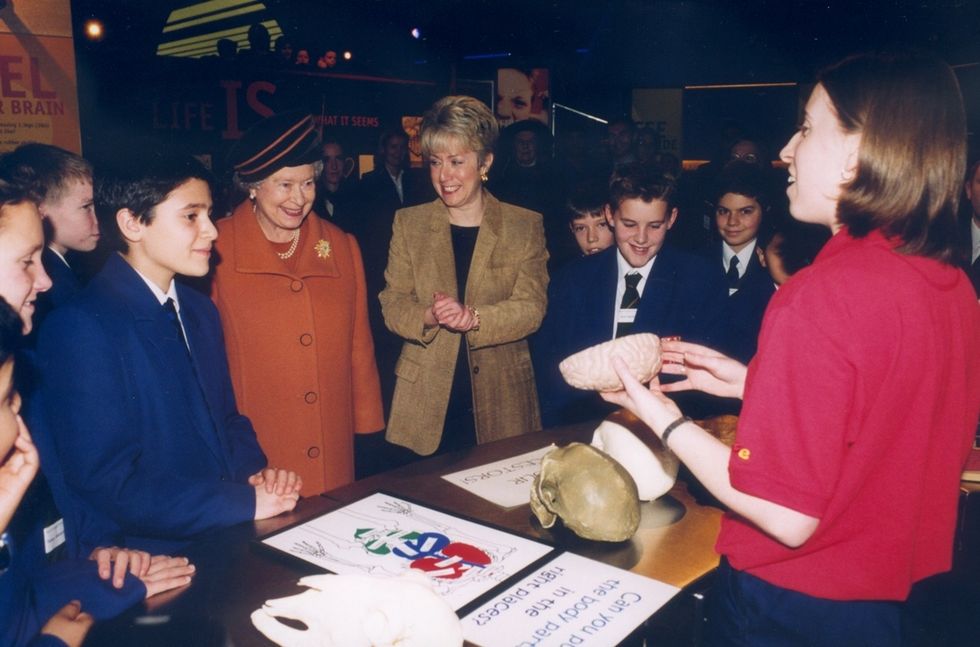 Exhibit presenter at Life showing students and visitors, including Queen Elizabeth II, a model of a human brain.