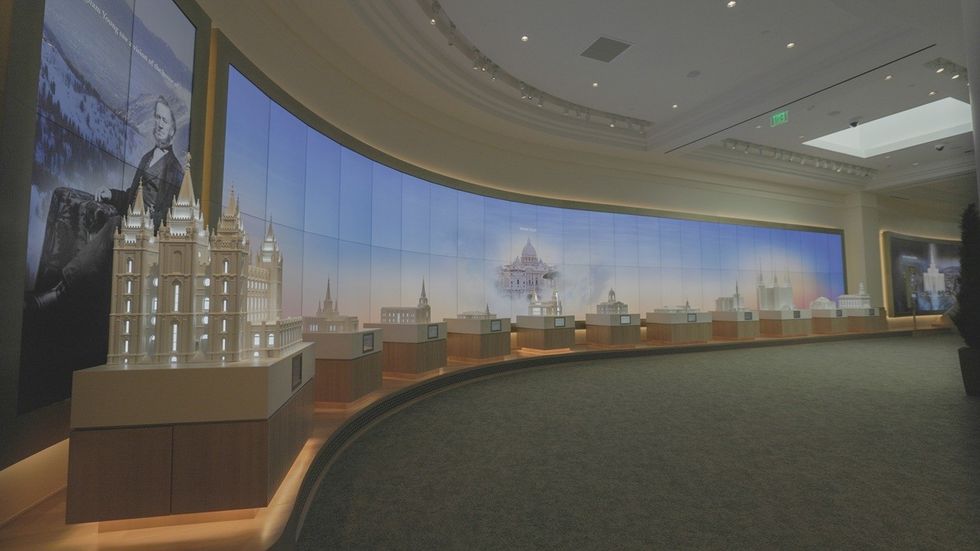 Exhibit room with illuminated temple models and large wall screens displaying temple images.
