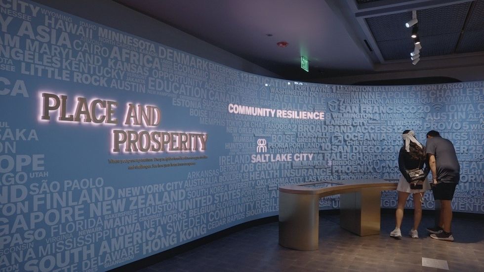 Exhibit with "Place and Prosperity" text, people interacting with a display.