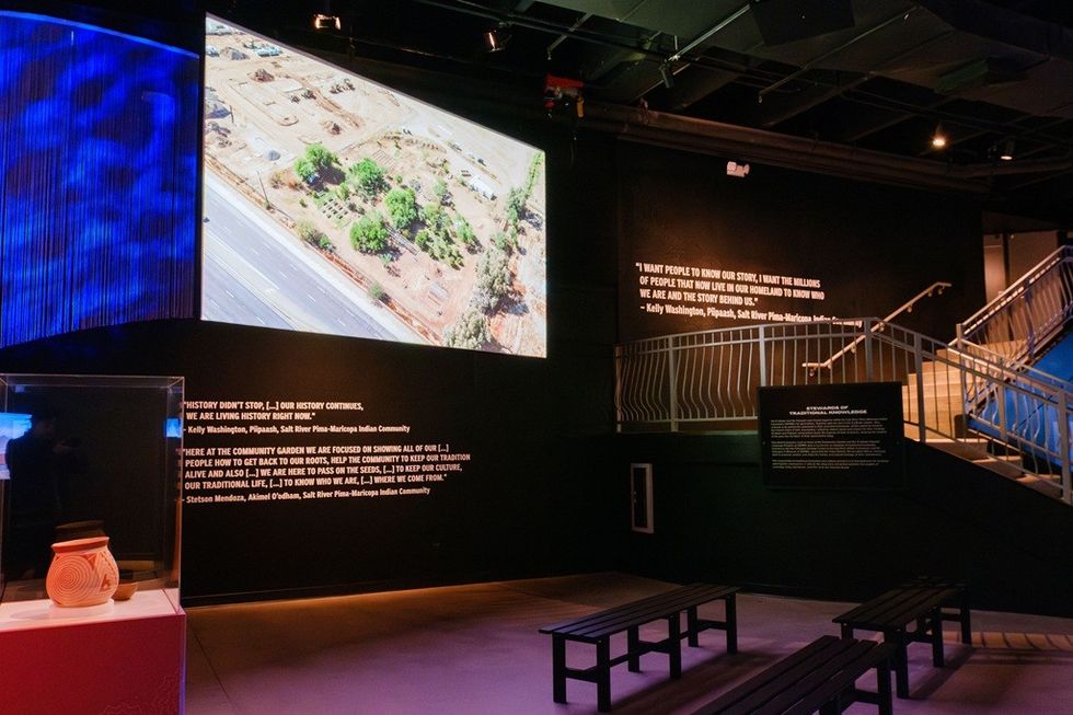 Exhibit with projection, quotes on walls, and benches in a museum setting.
