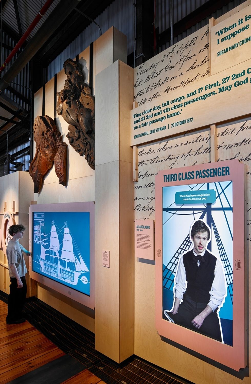 Exhibit with ship imagery and passenger quotes; person interacting with display.