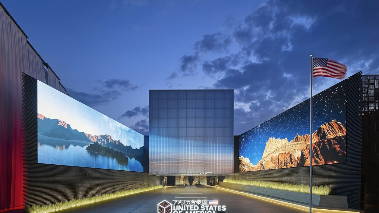 Expo Osaka 2025 US pavilion with large landscape displays and a waving flag at dusk.