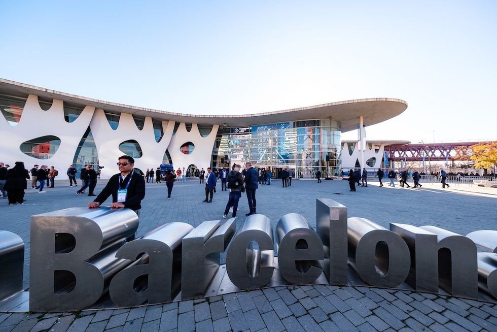 Exterior of a modern building with a large "Barcelona" sign and people walking around.