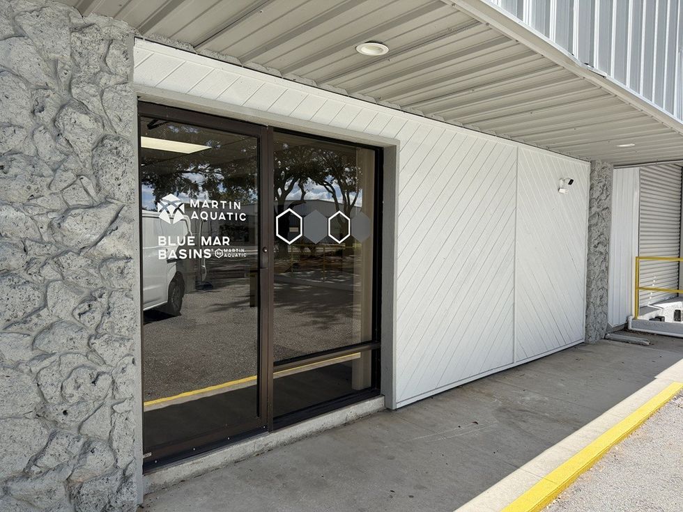 Exterior view of a storefront with a glass door and stone-textured wall.