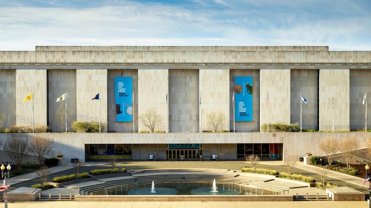 Facade of the Smithsonian's National Museum of American History with flags and banners.