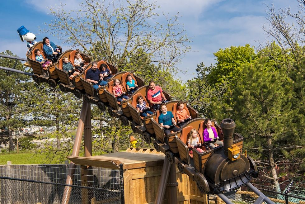 Families enjoy a ride on a Snoopy-themed roller coaster with a playful train design.