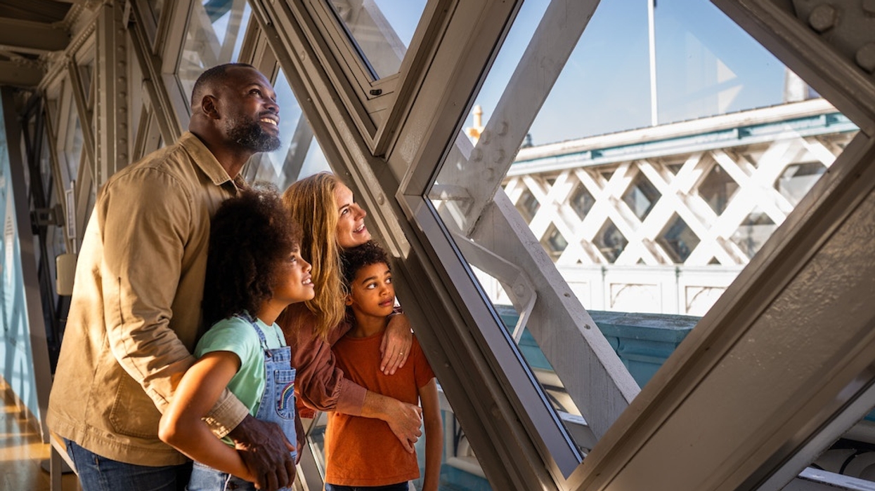 Family admiring the view through glass panels on a Tower Bridge's elevated walkway.