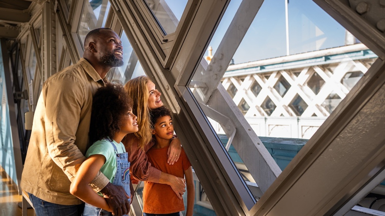 Family admiring the view through glass panels on a Tower Bridge's elevated walkway.