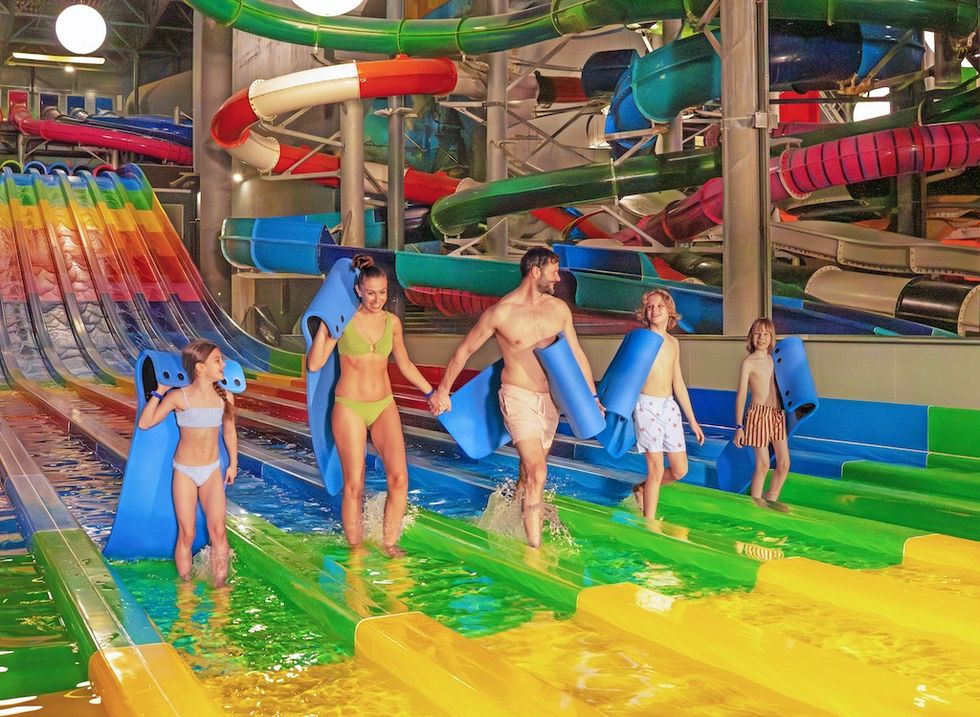 Family at Suntago Water World, carrying mats for multicolored slides.