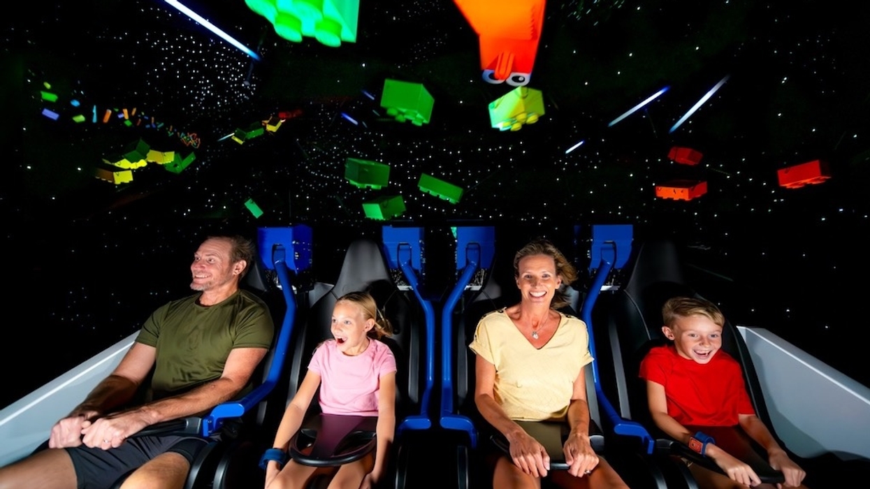 Family enjoying a colorful virtual reality ride with LEGO pieces floating above.