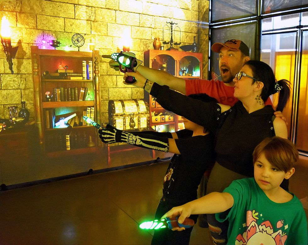 Family enjoying a magical adventure game with glowing wands in hand.