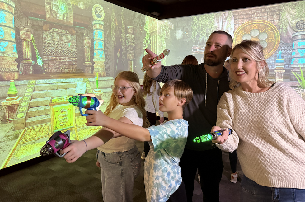 Family enjoying an interactive game with laser pointers in a vibrant virtual setting.