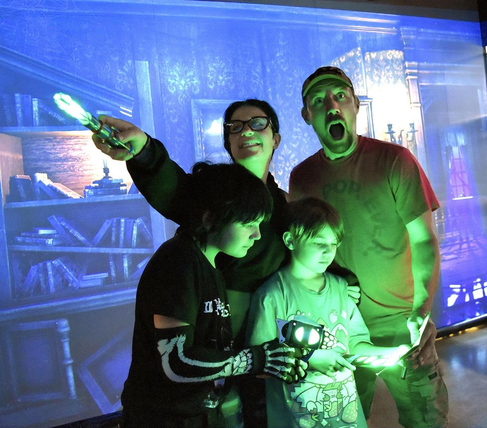 Family enjoying an interactive, glowing mystery game with blue background.