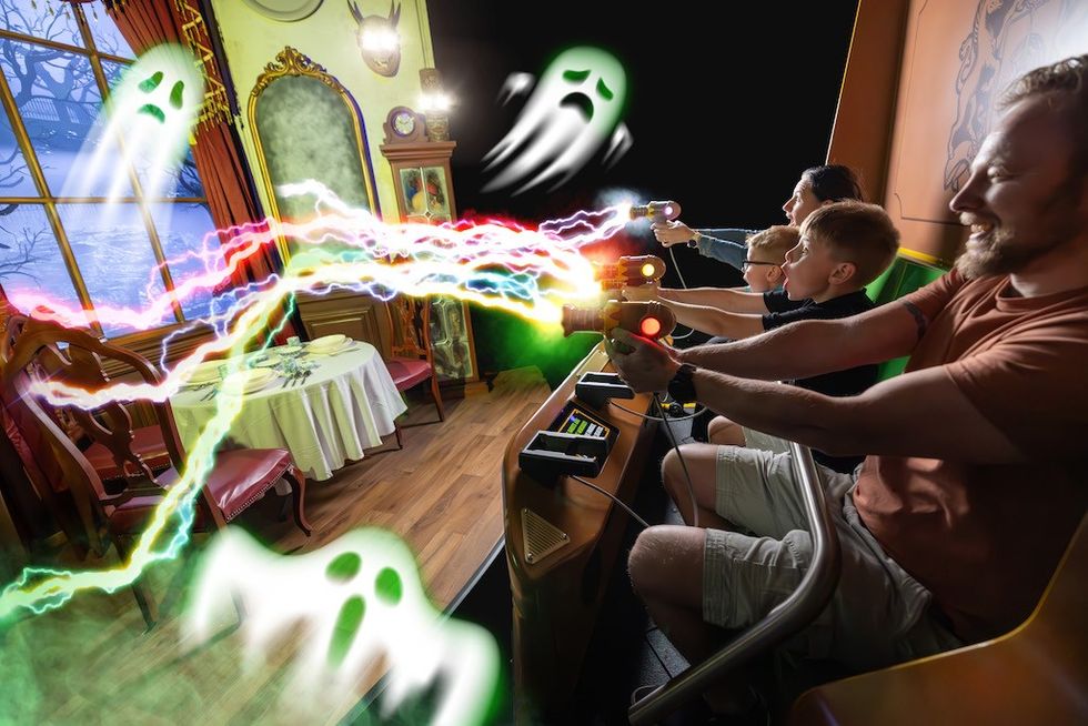 Family enjoys shooting ghost targets in an interactive ride called Ghostly Manor