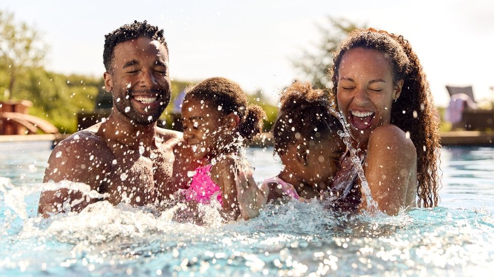Family joyfully splashing in a sunny pool, smiling and having fun.