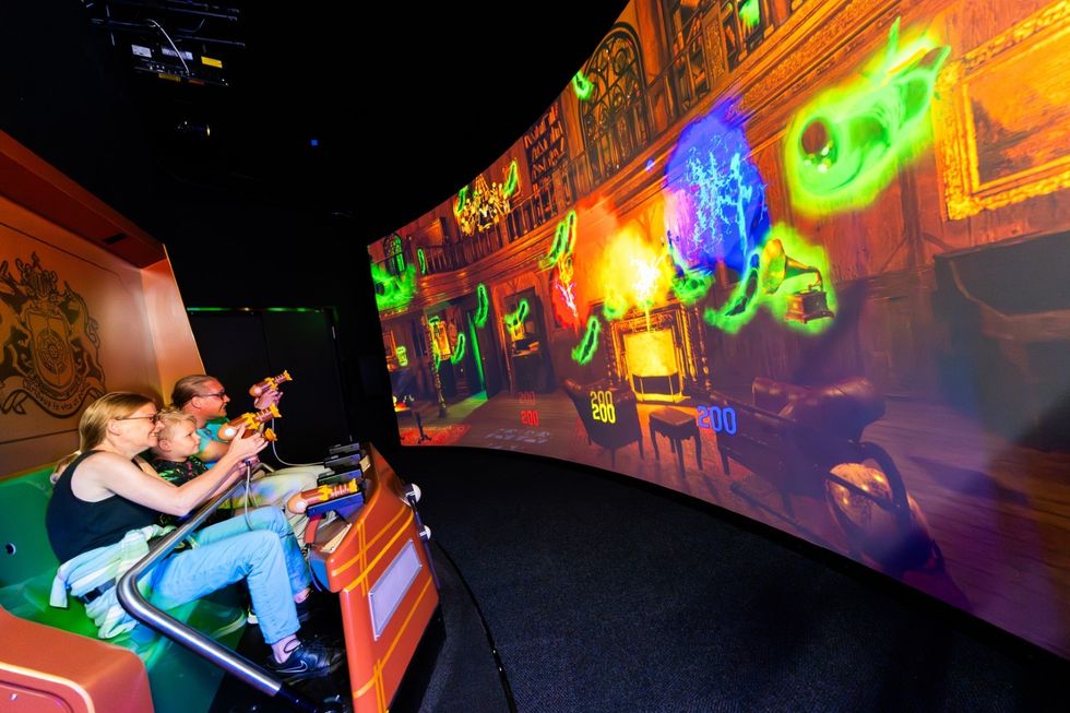 Family playing an interactive shooting game on an immersive curved screen.