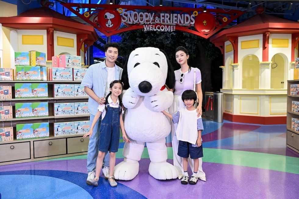 Family posing with Snoopy at "Snoopy & Friends Welcome" attraction.