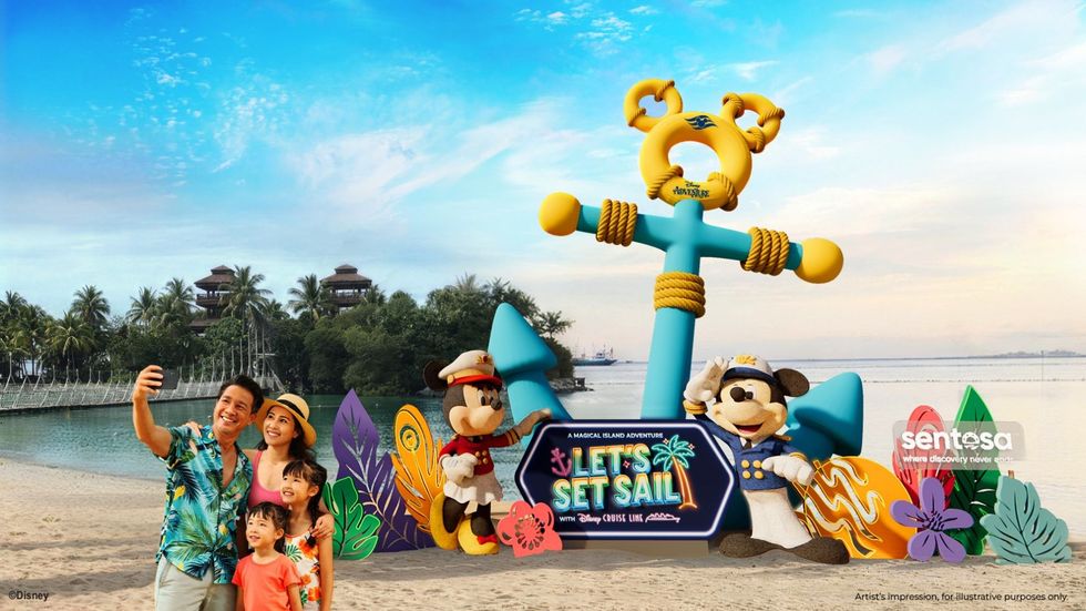 Family taking a selfie at the beach with Disney characters and a "Let's Set Sail" sign.
