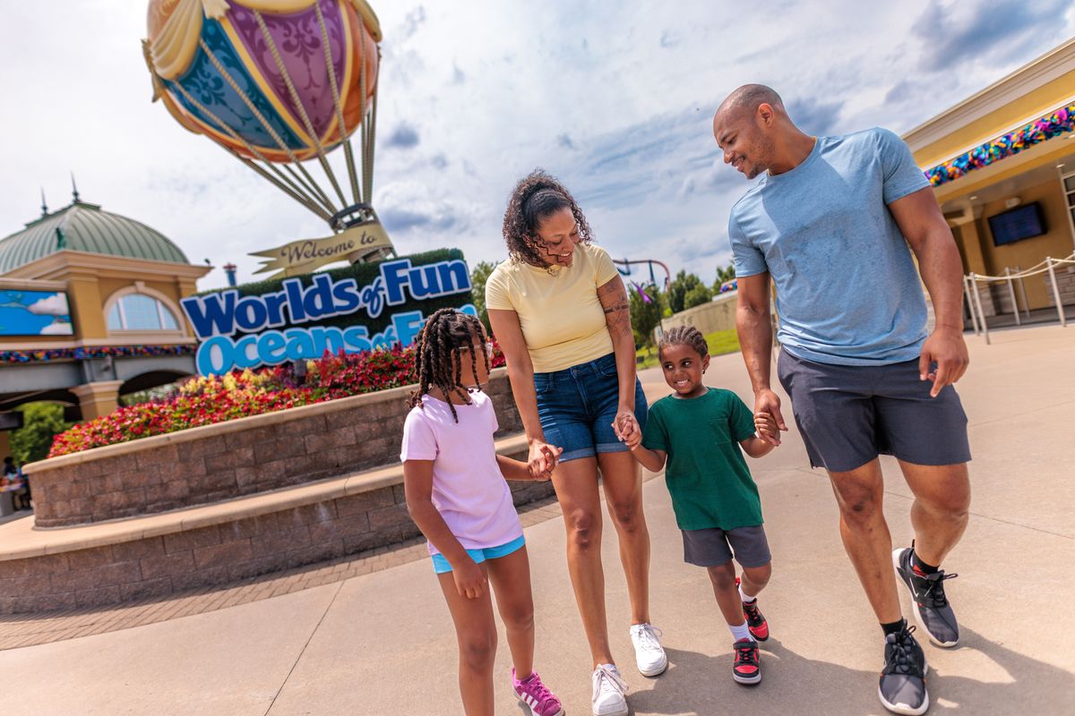 Family walking happily outside Worlds of Fun amusement park entrance.