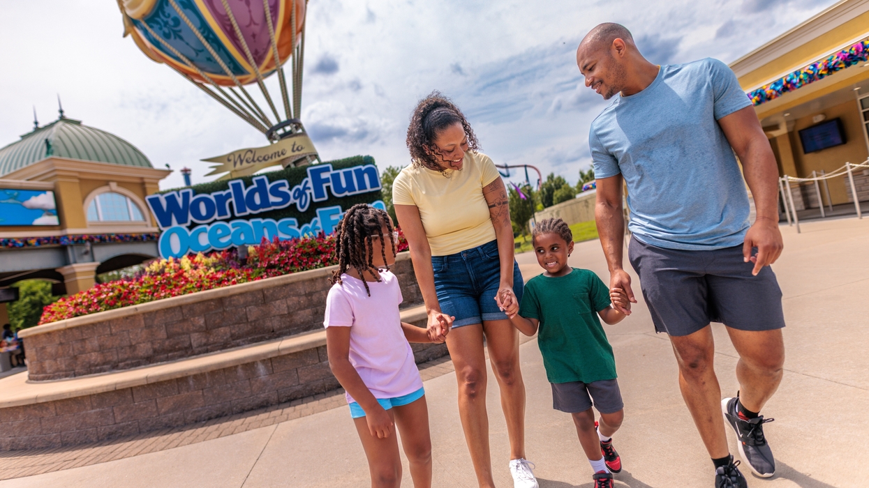 Family walking happily outside Worlds of Fun amusement park entrance.