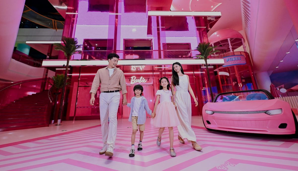 Family walking in vibrant pink Barbie-themed environment with a pink car at Magic World in China