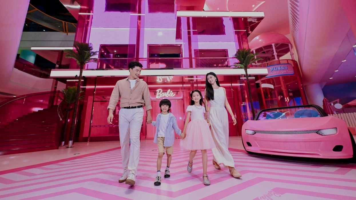 Family walking in vibrant pink Barbie-themed environment with a pink car at Magic World in China