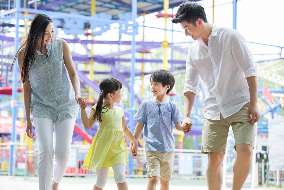 Family walking together at a colorful amusement park.