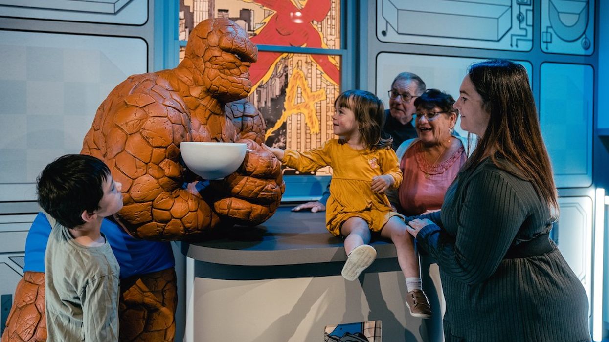 Family with The Thing statue at a superhero exhibit.