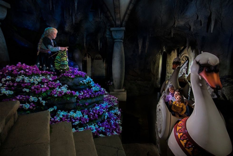 Fantasy ride with a figure knitting beside vibrant flowers and passengers in a swan boat.