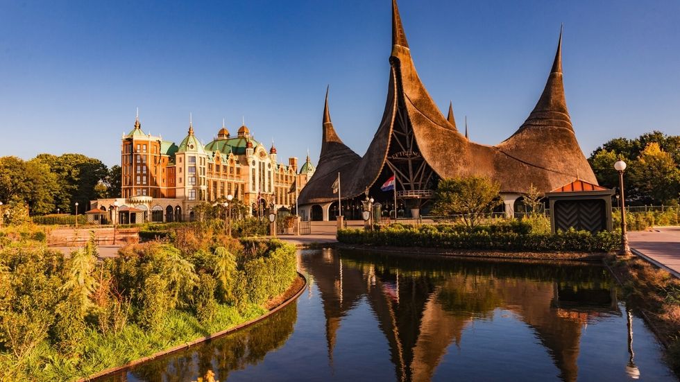 Fantasy-style buildings at Efteling with pointed roofs reflecting in a tranquil pond.