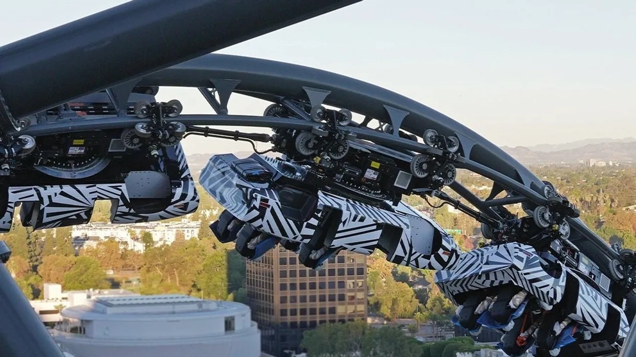 Fast & Furious roller coaster with striped cars on a track against a cityscape background.