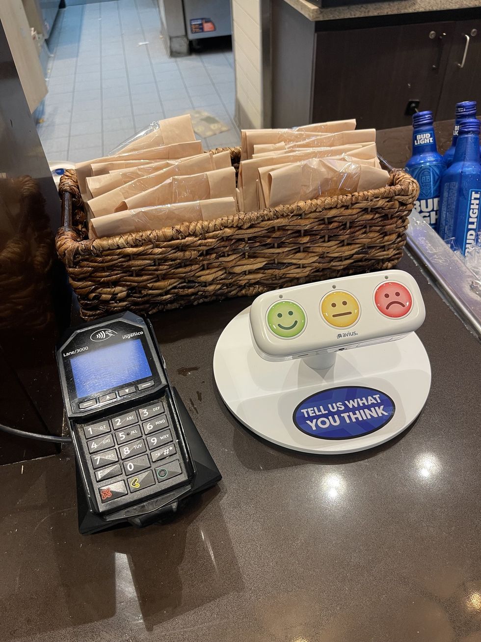 Feedback station with smiley, neutral, and sad face buttons next to a basket and payment terminal.