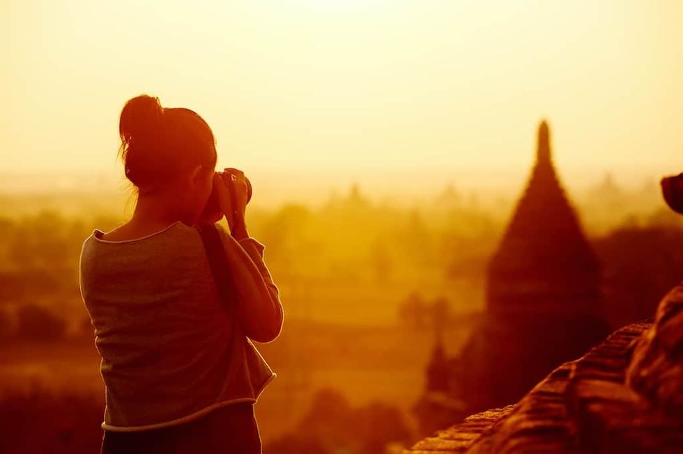 female traveller photographing temples at Bagan Myanmar Asia at sunrise