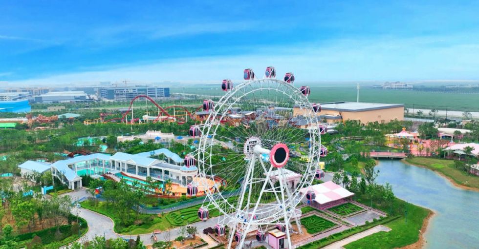 Ferris wheel in a colorful amusement park with greenery and a pond under a clear blue sky at fantawild wild land