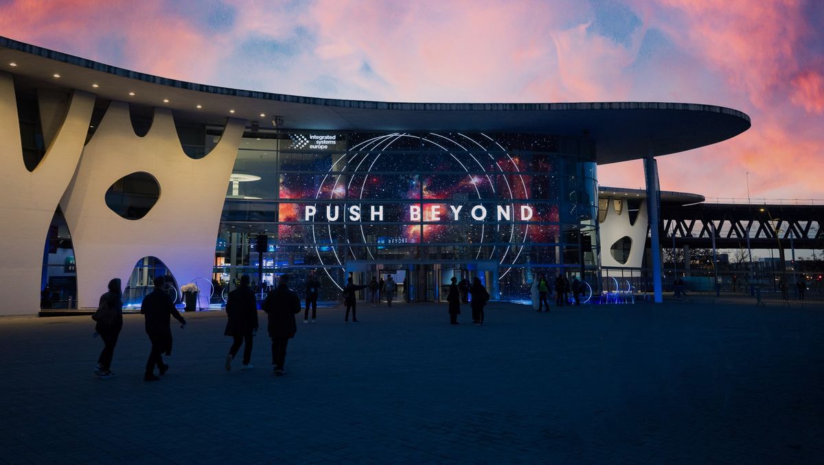 Fira Barcelona with ISE 2026 theme "Push Beyond" illuminated on the facade during sunset.
