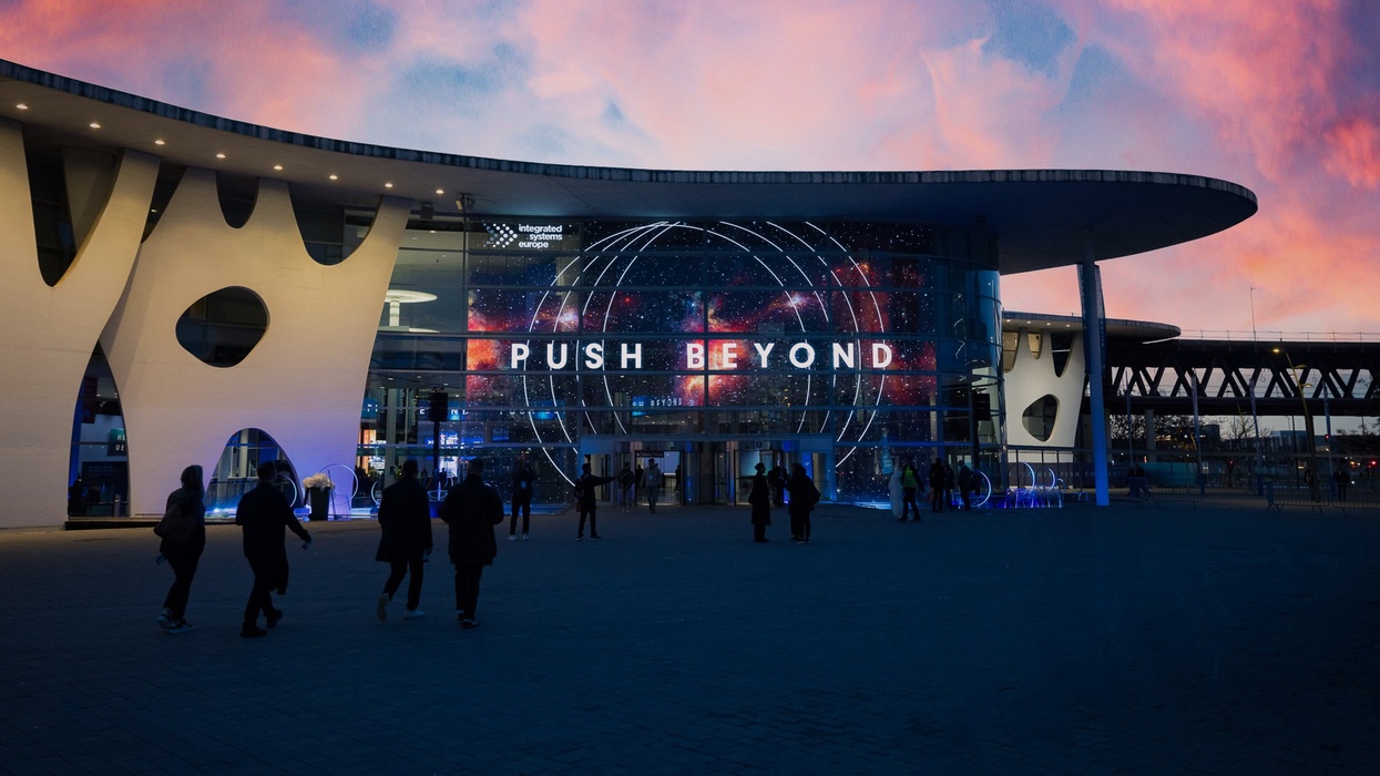 Fira Barcelona with ISE 2026 theme "Push Beyond" illuminated on the facade during sunset.