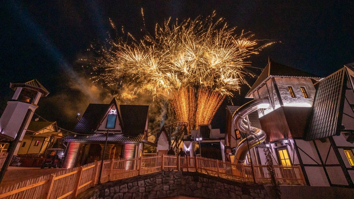 Fireworks illuminate a village scene at night with charming, rustic cottages and slides.
